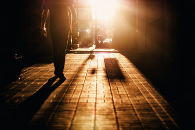 Rear view of man walking in alley at sunrise