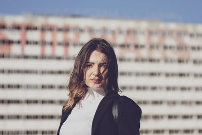 Portrait of young woman against building in city