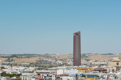 Buildings in city against clear blue sky