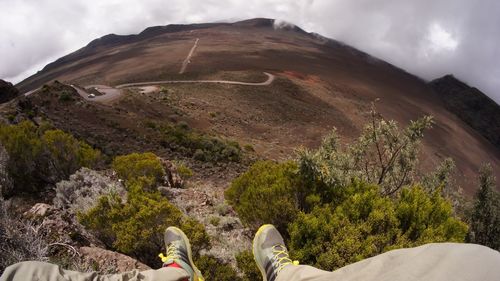 Low section of person standing on mountain against sky