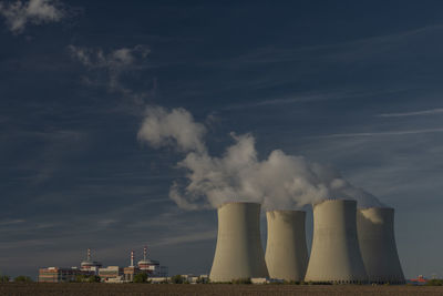 Smoke emitting from factory against sky