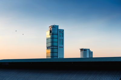 Low angle view of birds flying by building against sky