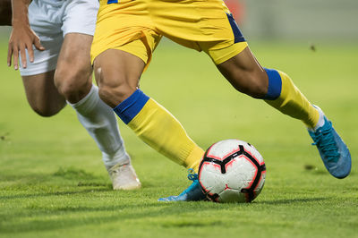 Low section of women playing soccer ball on grass