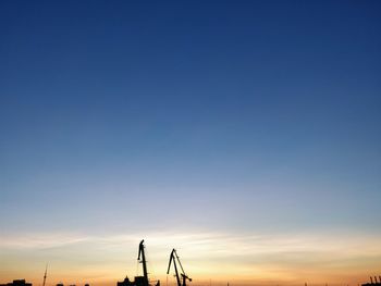 Silhouette cranes against sky during sunset