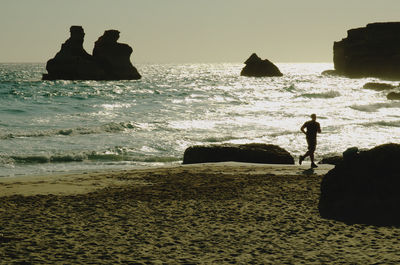 Silhouette people on beach against sky