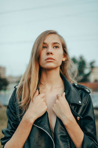 Portrait of young woman looking away against sky