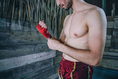 Full length of shirtless man holding umbrella