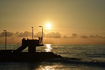 Silhouette of pier on sea during sunset