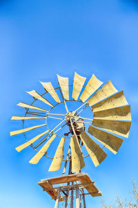 Low angle view of ferris wheel against clear blue sky