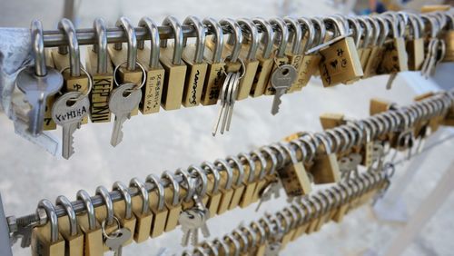 Close-up of padlocks and keys hanging on railing