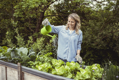 Woman holding ice cream cone against plants