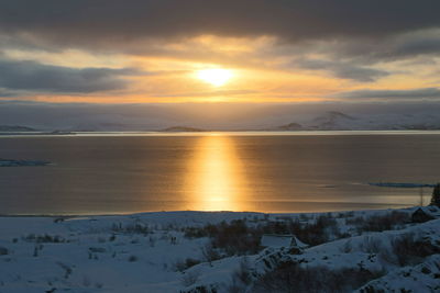 Scenic view of snow covered beach against sky during sunset