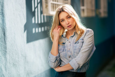 Portrait of beautiful young woman standing against built structure