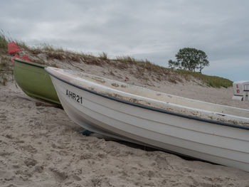 Boat moored on beach against sky