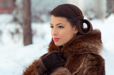 Close-up portrait of young woman with snow