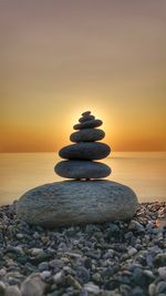 Stack of stones in sea during sunset