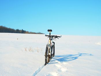 Bicycle on snow covered land against sky