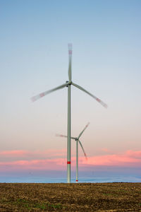 Low angle view of wind turbine against sky during sunset
