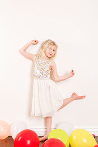 Full length of a beautiful girl with balloons against white background