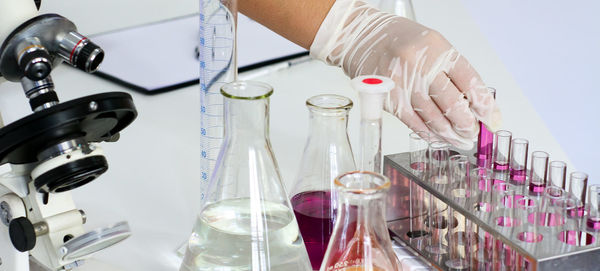 Cropped hand of person on holding test tube with chemical in rack 