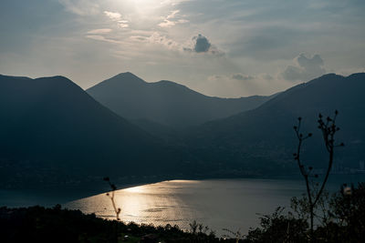 Scenic view of lake and mountains against sky at sunset