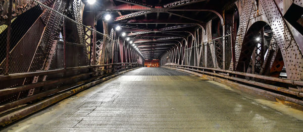 Empty road in illuminated tunnel at night