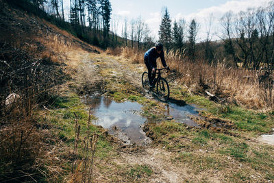 Full length of woman riding bicycle in forest