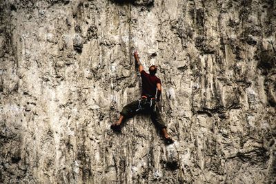 Rear view of male athlete climbing on rocky mountain