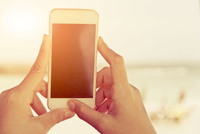 Cropped hands of woman using mobile phone outdoors