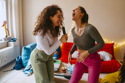 Playful young women enjoying music while singing at home