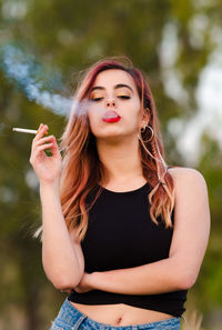 Portrait of a beautiful young woman holding cigarette
