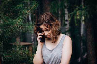 Young woman talking on mobile phone in forest