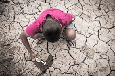 High angle view of boy watering barren ground