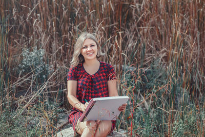 Portrait of a smiling young woman holding plants