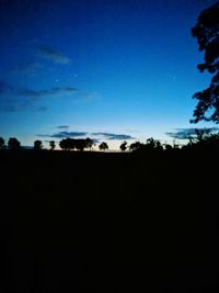 Silhouette landscape against clear blue sky at night