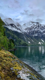 Scenic view of lake by snowcapped mountains against sky