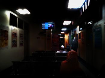 Rear view of woman sitting in illuminated building