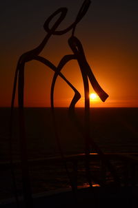 Silhouette beach against sky during sunset