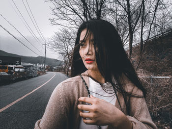 Portrait of young woman on road against sky