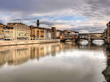 Ponte vecchio over arno river against cloudy sky