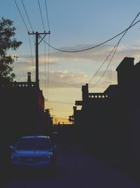 Cars in city against sky during sunset