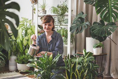 Portrait of young woman holding potted plant