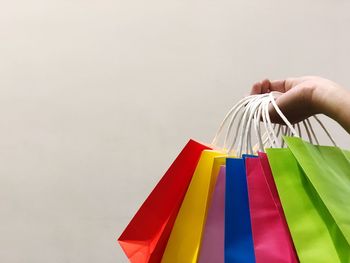 Close-up of person multi colored shopping bags over white background