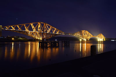 Illuminated bridge over river at night