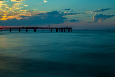 Pier over sea against sky during sunset