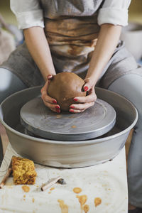 Midsection of female potter molding clay in workshop