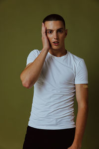 Portrait of young man standing against wall