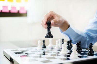Cropped hand of man playing chess