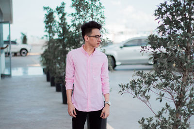 Young man standing in city against sky