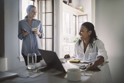 Cheerful female entrepreneurs in living room at home office